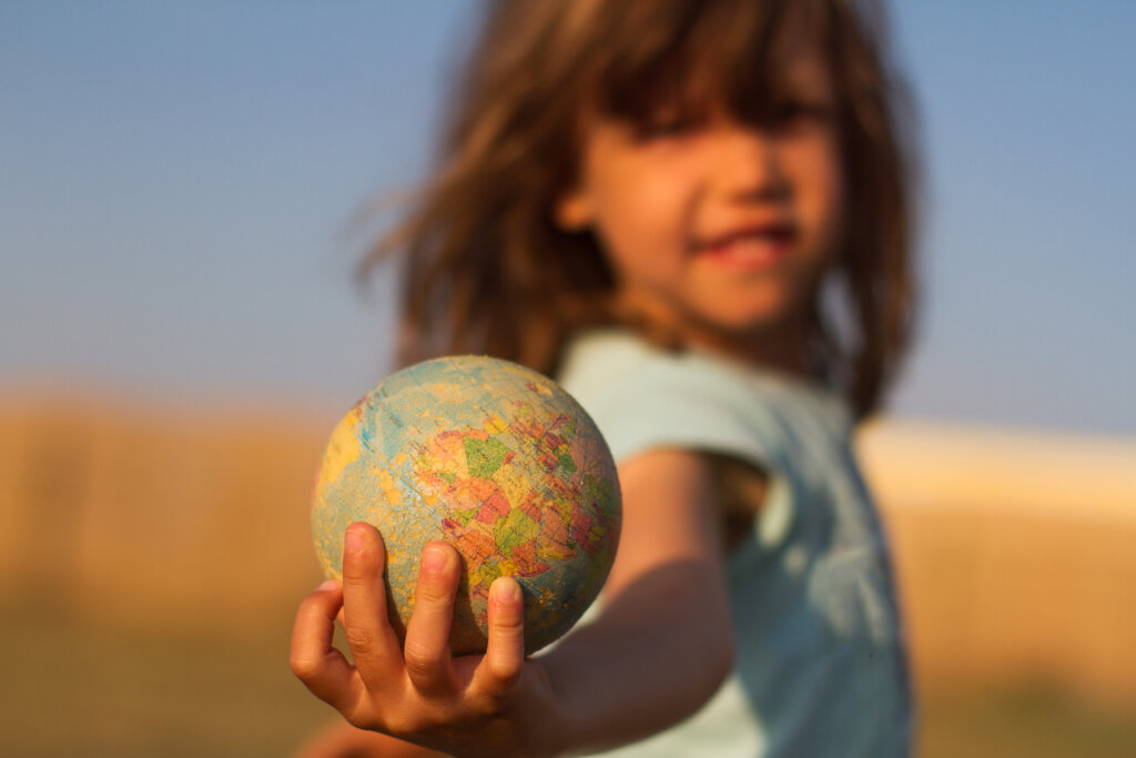 Niño con bola del mundo en la mano