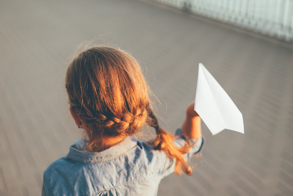 Niña con un avion de papel.