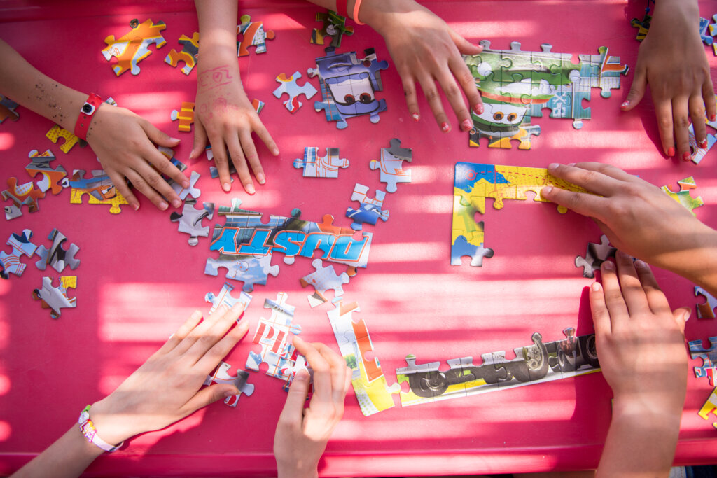 Manos de varios niños montando un puzzle