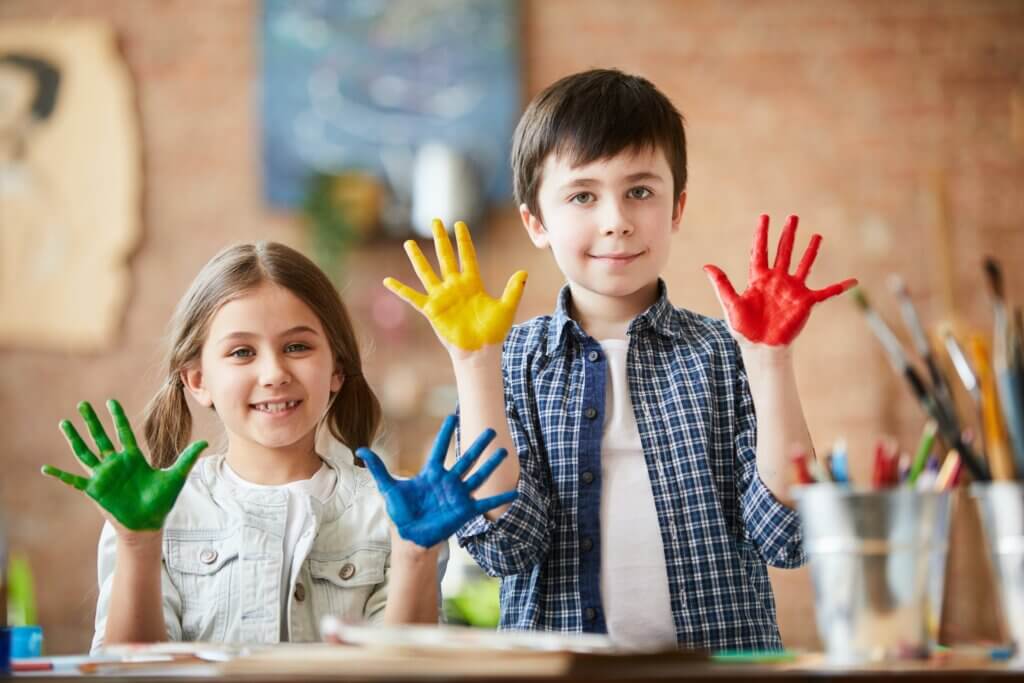 Niños mirando a la cámara y haciendo manualidades en casa
